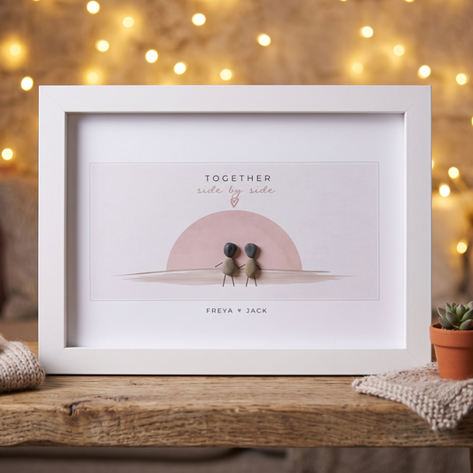 Together couple pebble picture in front of fairy lights: Together side by side, two pebble people