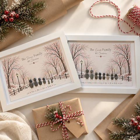 Two personalised Christmas Walk family pebble pictures in white frames beside a wrapped Christmas present