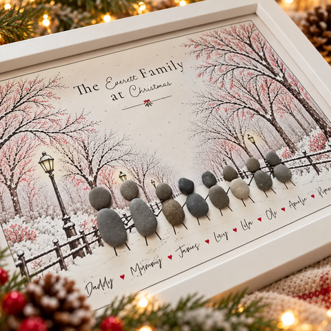 Close-up of a Christmas Walk pebble picture: pebble family walking past lamp posts in the snow, each name written underneath