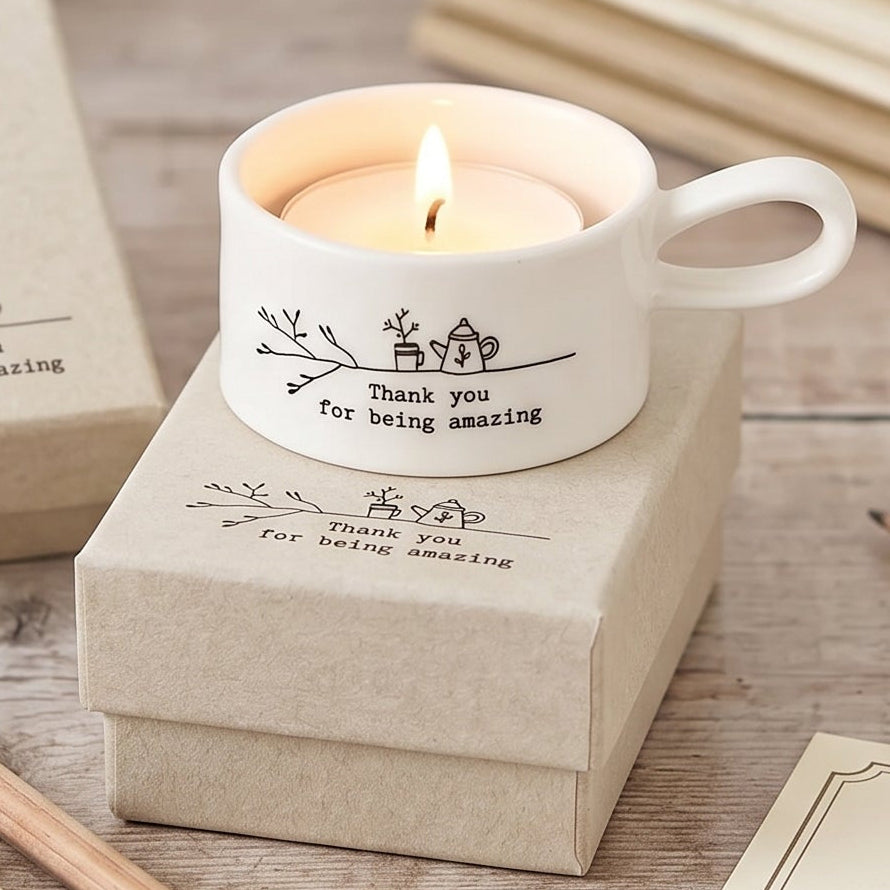 Candle in a mug with personalized message on a wooden surface with notebooks and pencils.