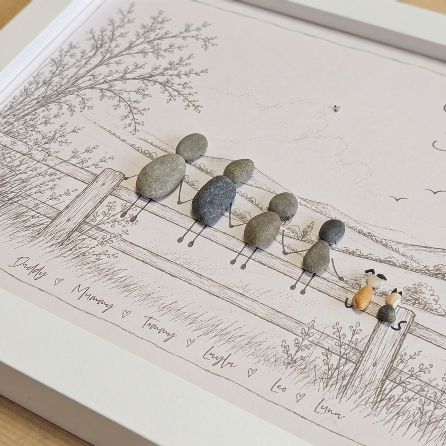 Close-up of a pebble family, dog and cat on a sketched fence with their names written underneath