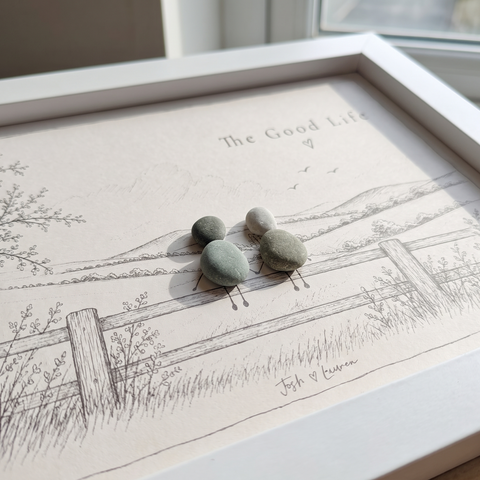 Close-up of two pebble people holding hands on a sketched fence with the names Josh and Lauren