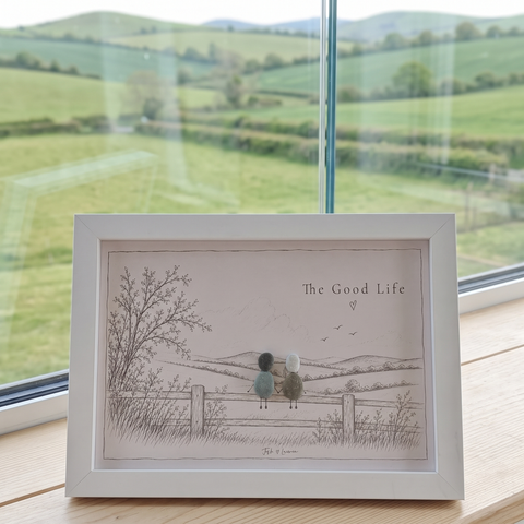 ‘The Good Life’ couple pebble picture in front of a window overlooking rolling green hills