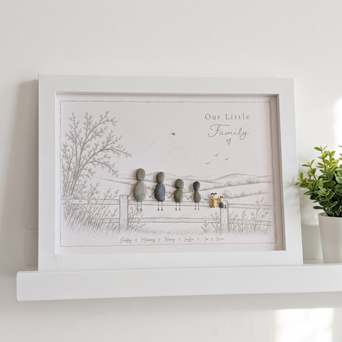 ‘Our Little Family’ pebble picture on a white floating shelf against a bright white wall