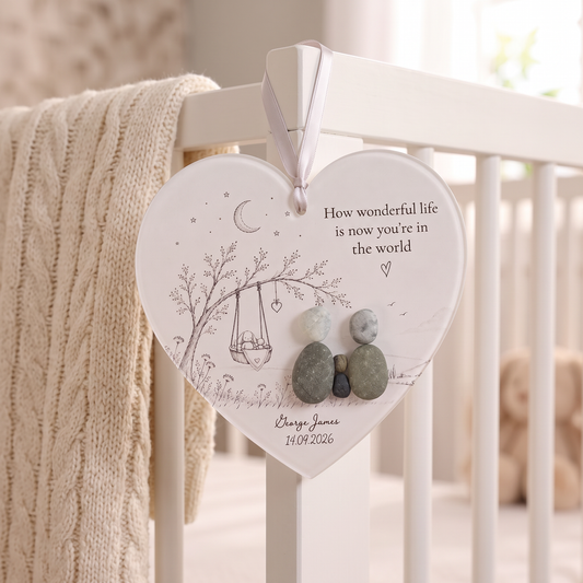 Personalised new baby pebble heart hanging on a cot