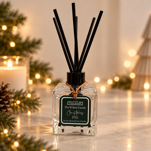 Personalised Christmas reed diffuser with green family tag on a simple warm twinkle lights background
