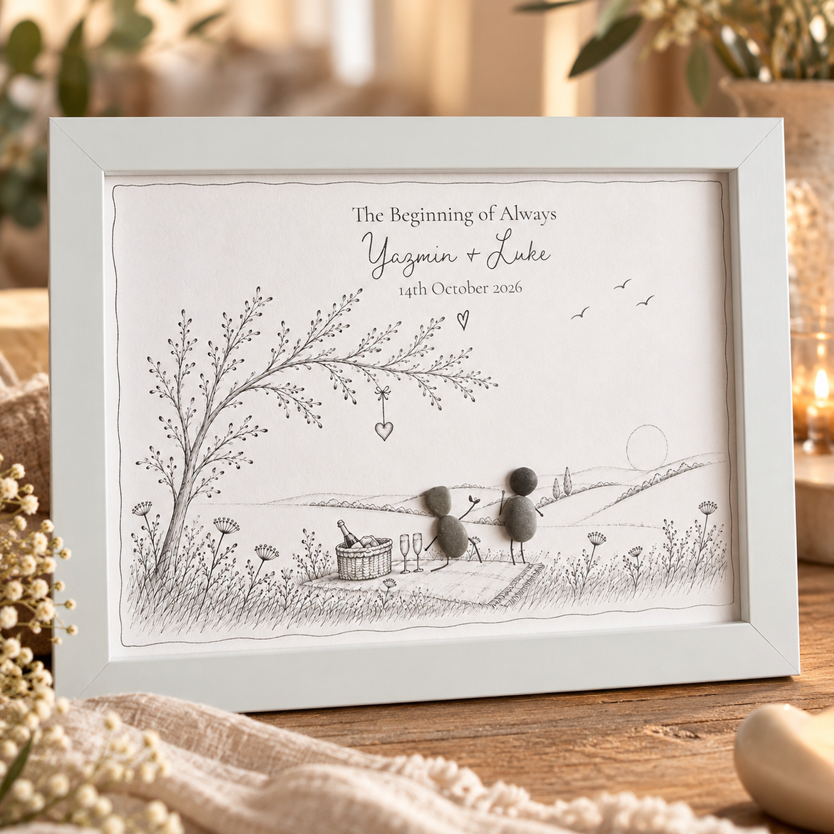Storybook engagement pebble picture in a white frame: a pebble proposal picnic beneath a tree, with ‘The Beginning of Always’, the couple’s names and the date
